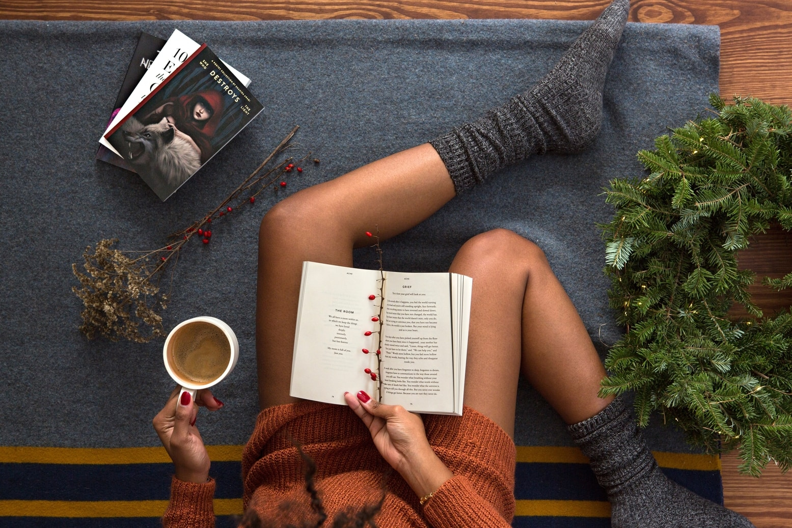 woman laying on the couch drinking coffee and reading a book