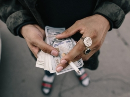 a Man preparing for a date holding his money while smoking a cigarette.