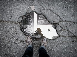 a mans reflection in a puddle of water