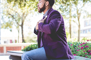 Black Men wearing purple blazer with jeans sitting down