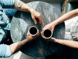 Man and woman sitting at a table on a date drinking coffee and asking each other questions