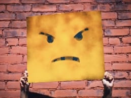 Demon poster of an angry face against a brick wall