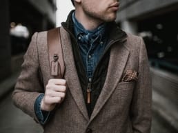 Alpha male wearing a brown blazer, and satchel walking down a corridor