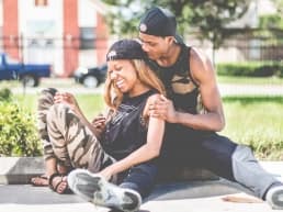young happy African American couple sitting on the ground at a park