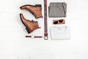 Arrangement of a men clothing. Shoes, belt, pants, white shirt, black shades, brown watch.